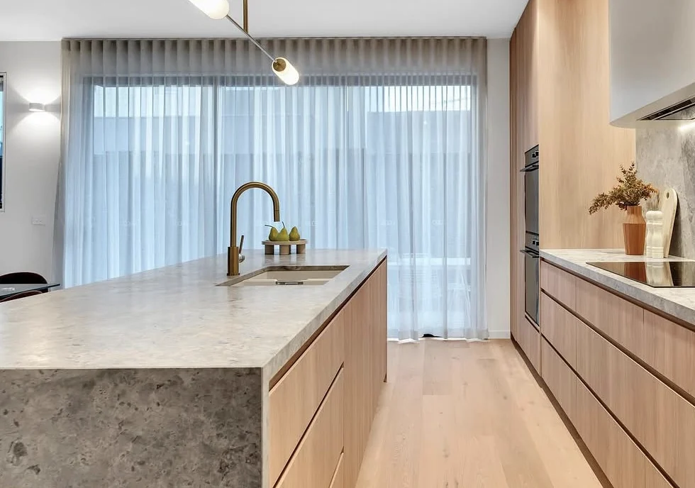 Light timber cabinetry, a pale stone island and dark joinery in a Workform kitchen